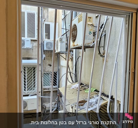 חלון עם סורגים לבנים ומזגנים בחוץ